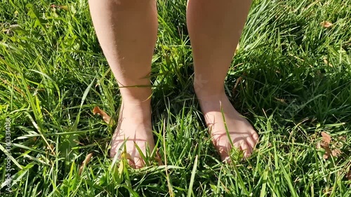 Children's feet trample on green grass. Green lawn. Summer video. Child. Feet in grass