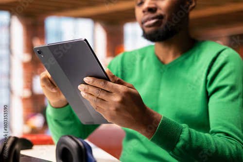 Obraz na plátne Man at home happily scrolling on tablet touchscreen to check social media feed