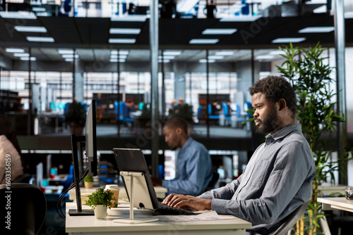 Male executive analyst finalizes a financial report and reviews data, developing a forecast for organizational progress. Black man engaged in task management and strategy planning.