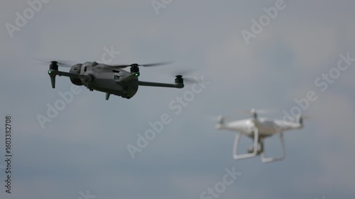 Two drones hover side by side in the air, with a focus shift smoothly moving from one drone to the other