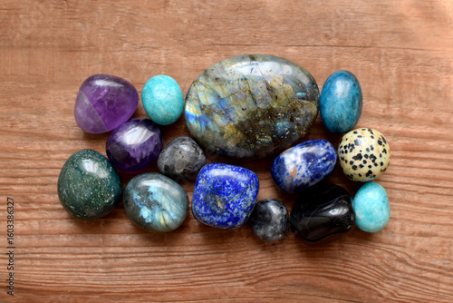 Polished labradorites, amethysts, lapis lazuli, kyanites on a wooden background. Beautiful natural stones, healing crystals, semi-precious stones.