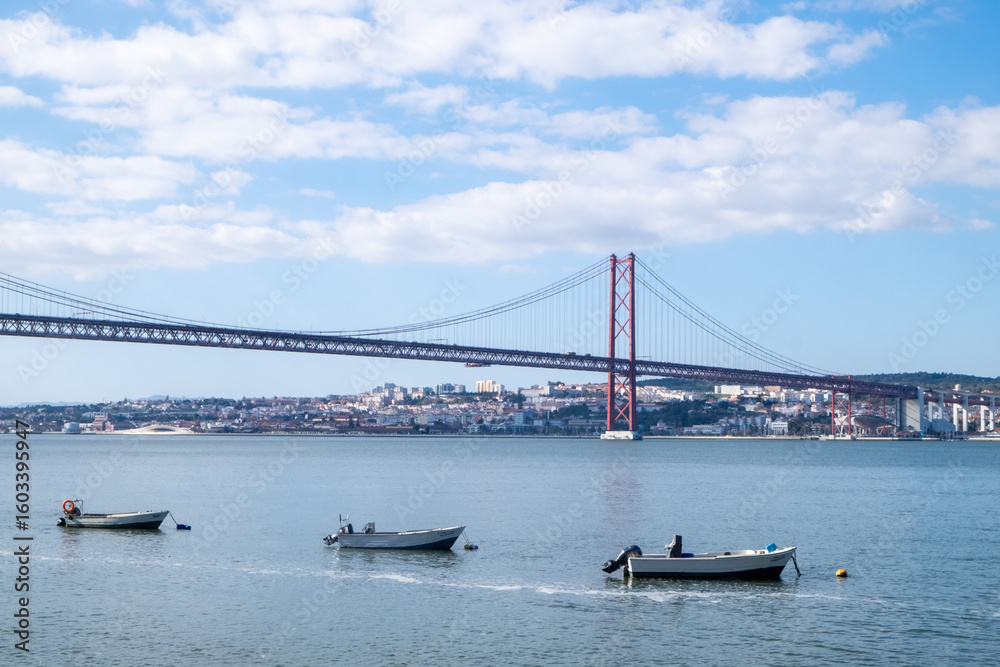 Naklejka premium Small fishing boats and a palm tree on the Lisbon waterfront overlooking the Tagus River.
