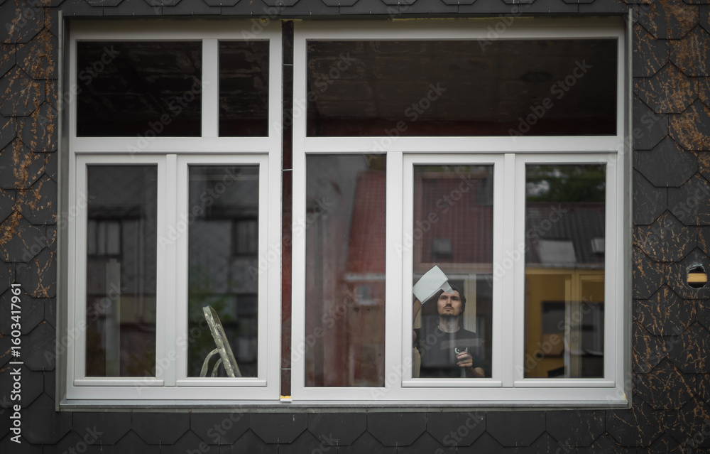 Fototapeta premium A young worker washes windows after construction work.