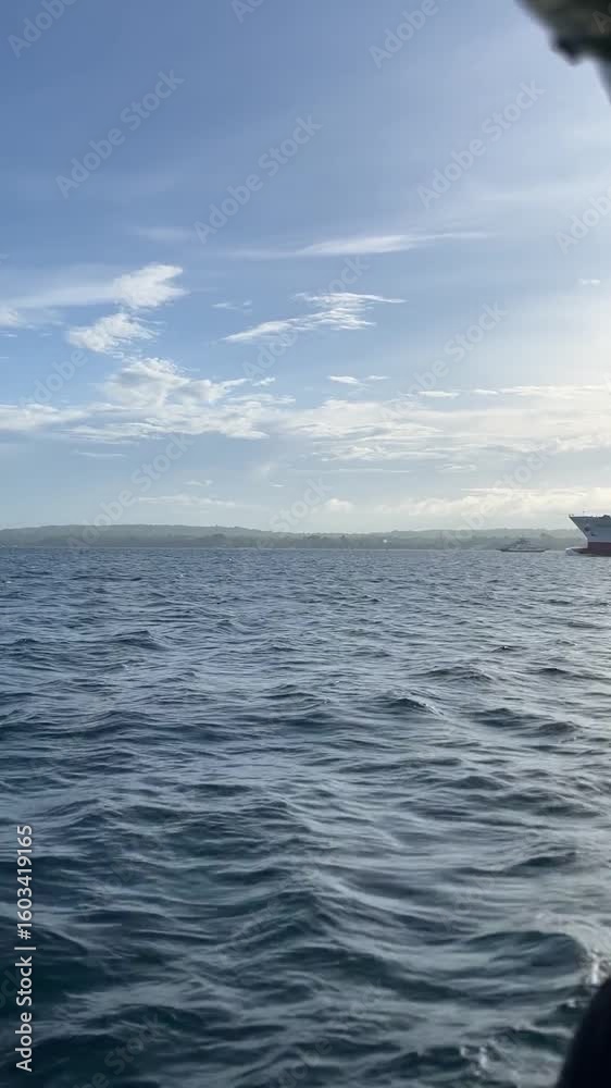Calm blue ocean with a large cargo vessel navigating the waters.