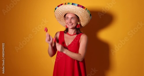 Happy woman in sombrero hat playing maracas on yellow background