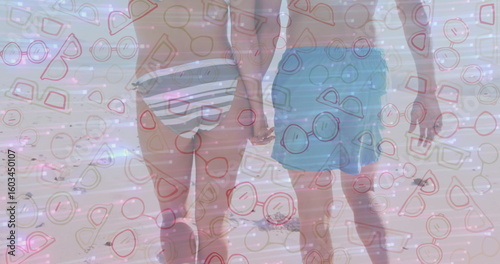 Bild auf Leinwand Walking couple holding hands along beach shoreline, with striped bikini bottom a