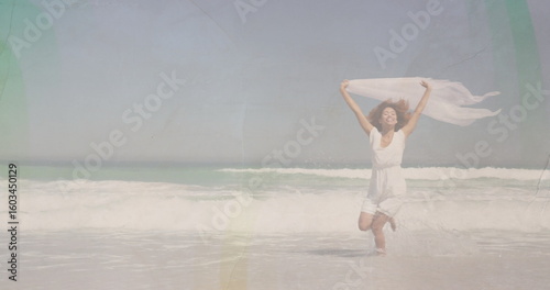Tableau sur toile Running woman wearing white sleeveless dress along shoreline, white sheer scarf