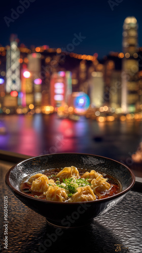 A bowl of dumplings with green onions in broth against a blurred cityscape at night in hong kong