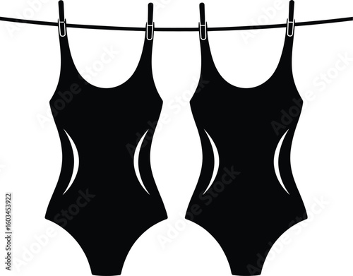 Two black one piece swimsuits hanging on a clothesline