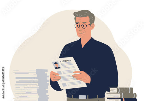 Man reading resumes wearing glasses among piles of papers and books