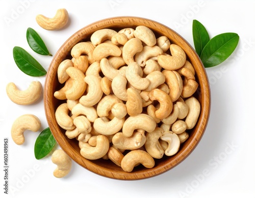 Top view of Roasted cashew nuts in wooden bowl with pile of cashew nuts on white background.