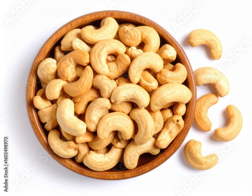 Top view of Roasted cashew nuts in wooden bowl with pile of cashew nuts on white background.