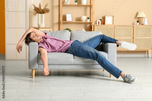 Weary young man lying on so...