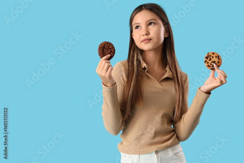 Canvastavla Thoughtful teenage girl with different cookies on blue background