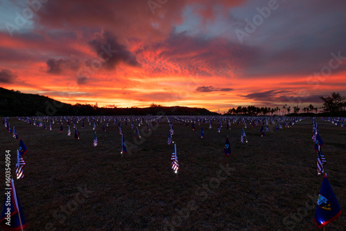 Memorial Day display with US flags and Guam flags that are lit with LED lights at Asan Beach Park with a vivid sunset 