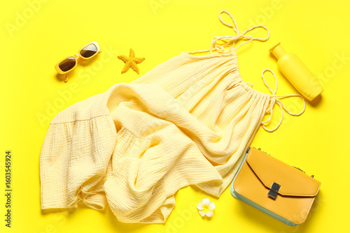 Foto Female summer dress with sunglasses, sunscreen and handbag on yellow background