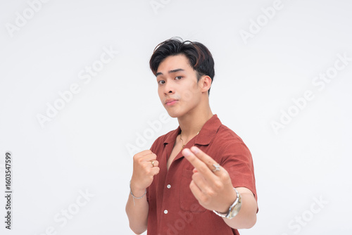 Konstfotografi A provoking young Asian man making a bold 'come here' gesture with his fist near his chest