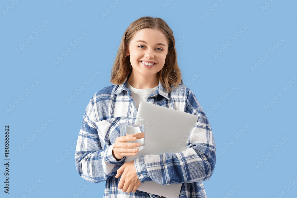 Young woman with glass of water and laptop on blue background Young woman with glass of water and laptop on blue background