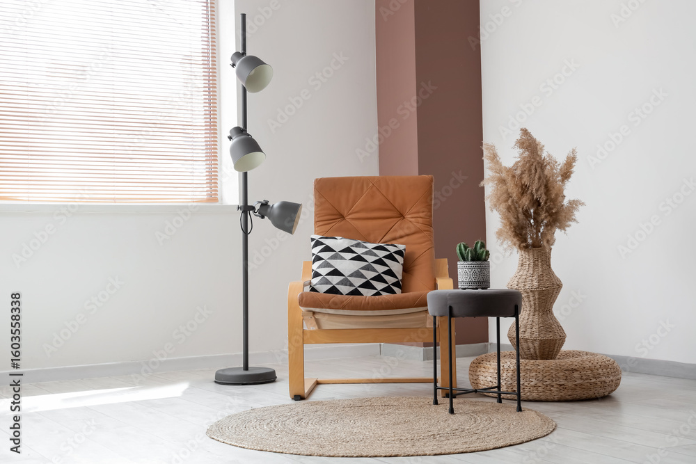 Fototapeta premium Comfortable armchair, floor lamp and vase with pampas grass near white wall in interior of living room