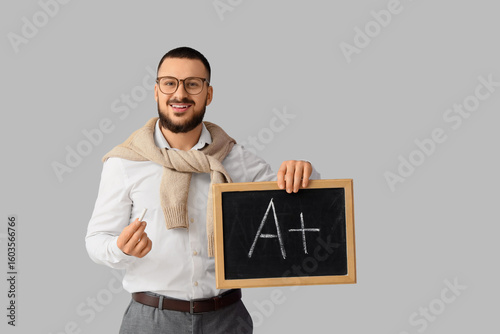 Male teacher holding chalkb...