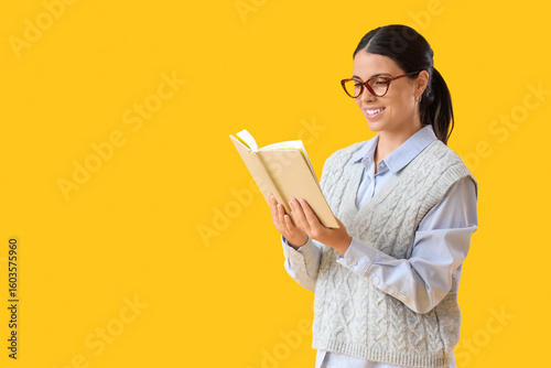 Beautiful woman reading book on yellow background