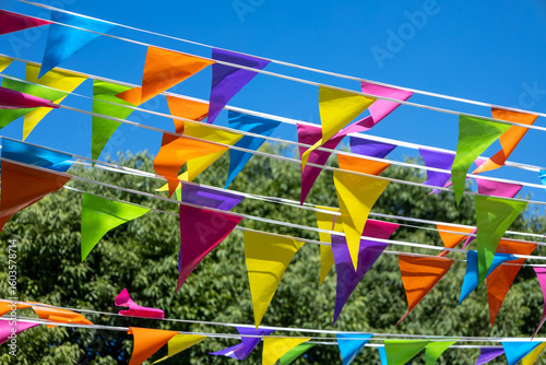 Colorful party pennant flags under blue sky.