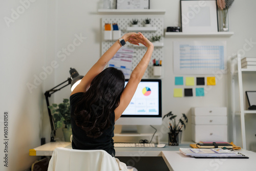 Office worker stretching arms at desk after work on computer