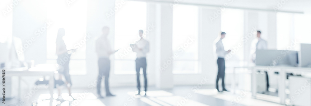 Obraz premium People in a bright office space with desks and large windows.