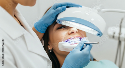 A dentist using an LED light for a cosmetic dental treatment on a female patient