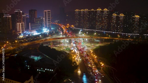 Nighttime city transportation illuminated by lights with aerial view capturing busy traffic and urban landscapes
