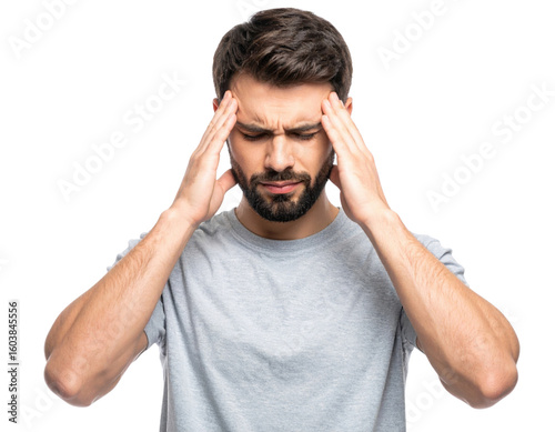 A young man with a beard wearing a gray t-shirt is touching his temples and appears to be experiencing a headache or deep concentration.