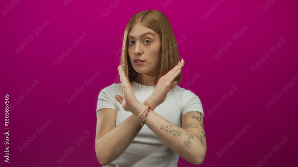 Obraz premium Young blonde woman making stop gesture with crossed arms against vibrant pink background