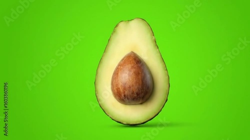 A halved avocado sits on its peeling against a green background