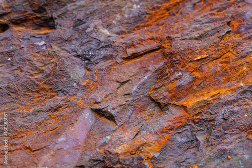 Bild auf Leinwand Close-up of colorful weathered rock surface with iridescent textures and rugged
