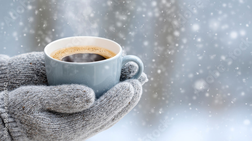 Cozy winter moment with a steaming coffee cup held in knitted gloves amidst falling snow