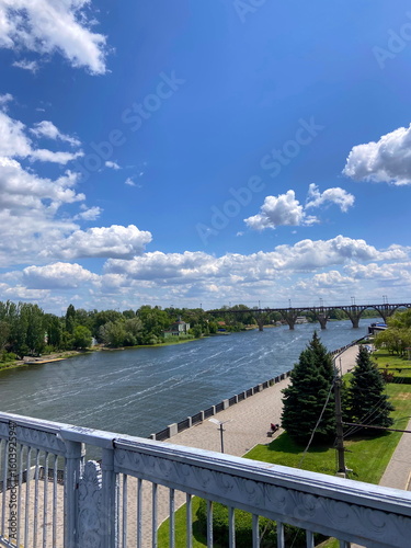 View of a comfortable pedestrian bridge across the Dnipro connecting the city of Dnipro with Monastyrsky Island on a hot sunny day.