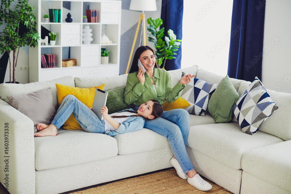 Obraz premium Happy woman with her daughter enjoying a relaxing weekend at home together, showcasing family bonding and modern lifestyle.