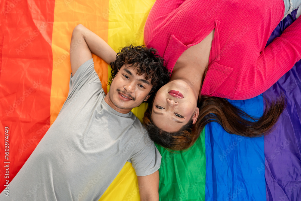 Obraz premium Portrait of Asian transgender woman and partner lying down on rainbow flag. 
