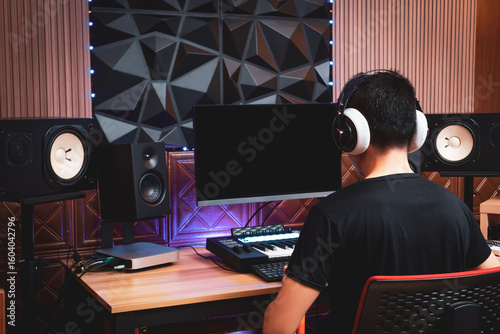 back of asian professional male music producer, arranger, composer working in home studio. music production concept