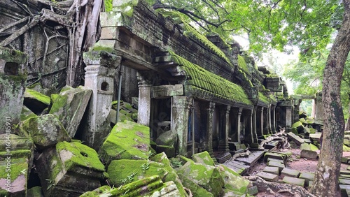 Ta Prohm, Cambodia - 3 July 2025. A vine-covered temple corridor with collapsed sections and mossy stones lies under dense canopy, where roots pierce through ancient masonry.