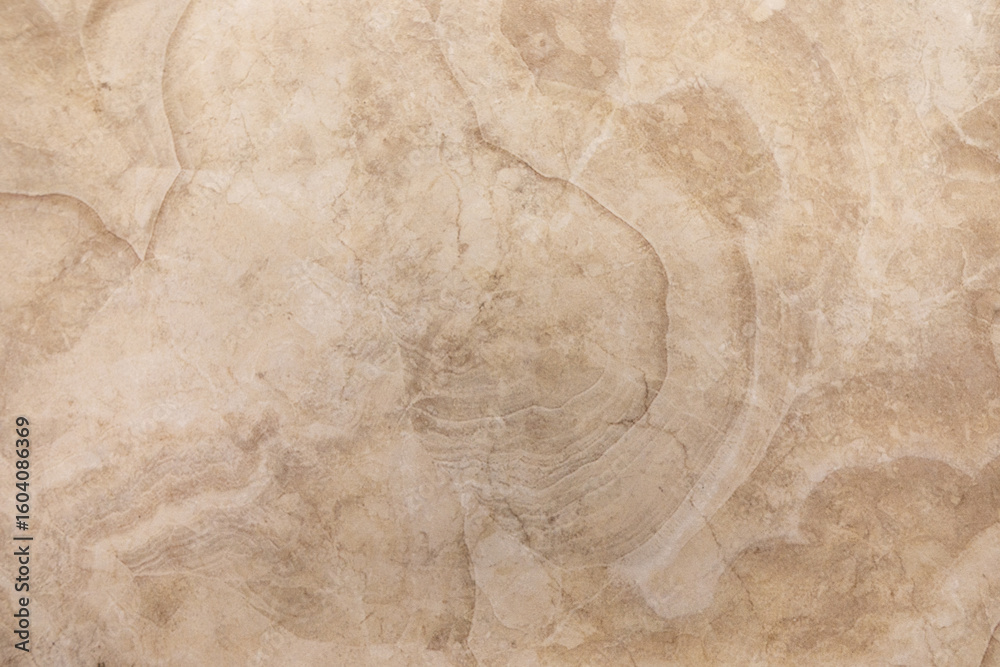 Sandy beige marble surface with subtle patterns and textures highlighted by natural light
