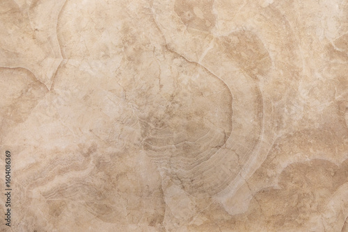Sandy beige marble surface with subtle patterns and textures highlighted by natural light