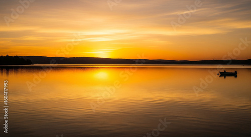 Golden Sunset Over Calm Lake with Small Boat Reflection


