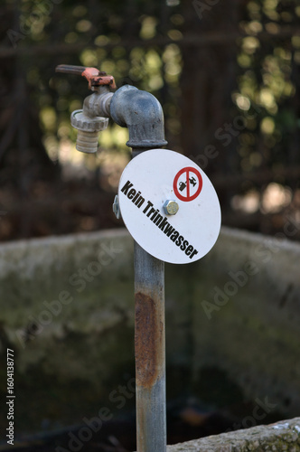 Old outdoor faucet with warning sign “Not for drinking water”.
