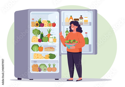 A woman stands in front of an open refrigerator, holding a bowl of salad, surrounded by fresh produce and food items.