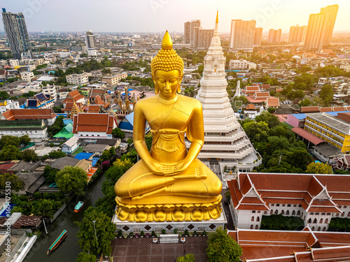 Canvastavla A boat was passing Big Buddha statue (Phra Buddha Dhammakaya Thepmongkhon ) in Wat Pak Nam Phasi Charoen temple located by the river during sunset