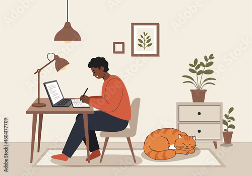 A dark-skinned man working from home, focused on a laptop and notepad, with a ginger cat resting nearby.