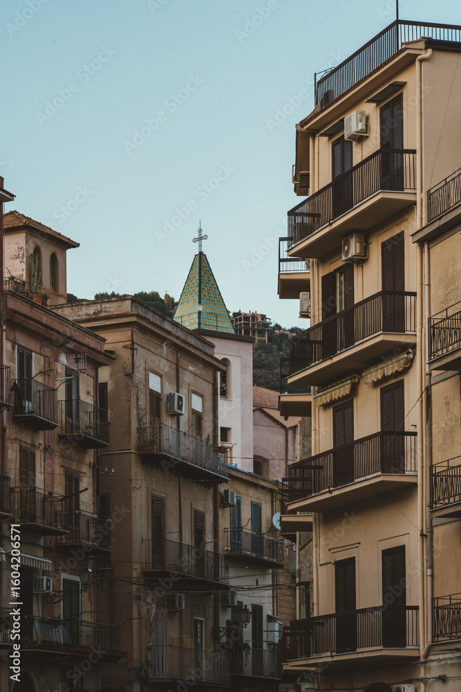 Fototapeta premium Church dome with cross between old residential buildings in southern Italy