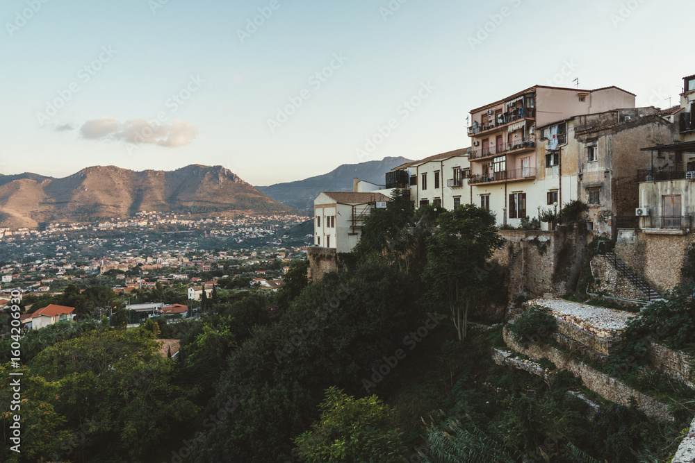 Obraz premium Houses on hillside overlooking valley and mountains at sunset in Sicily