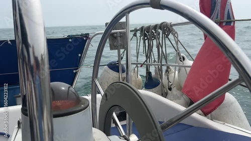 A sailing boat autopilot steering a yacht sailing downwind in light airs. The motor inside the wheel turns the wheel to keep the sailing vessel on its designated course.#3